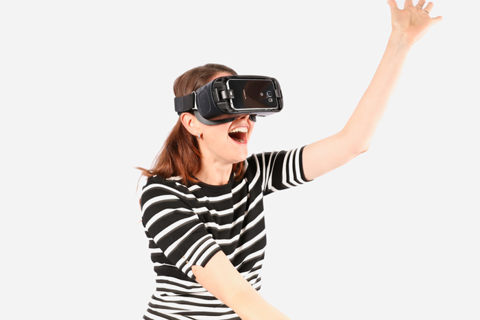 A woman uses a smartphone-based virtual reality headset. A woman uses a smartphone-based virtual reality headset.